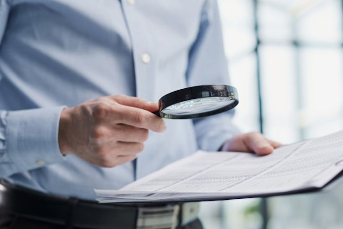 man-looking-through-magnifying-glass-documents-notebook.jpg man-looking-through-magnifying-glass-documents-notebook.jpg