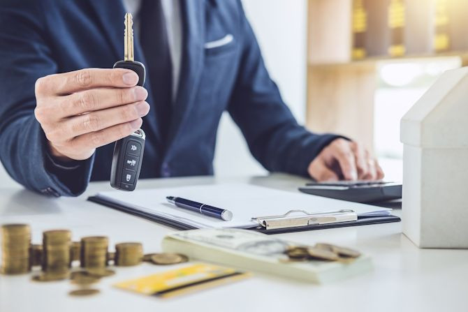 salesman-holding-key-calculating-price-selling-new-car-home-loan.jpg