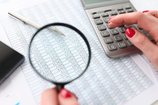 woman-counting-calculator-holding-magnifying-glass-document.jpg