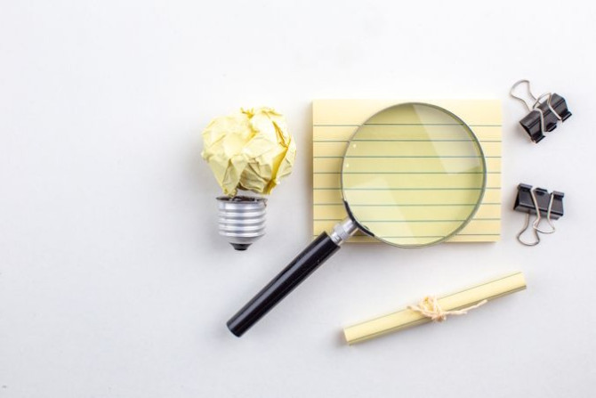 top-view-lupa-sticky-note-binder-clips-rolled-up-paper-tied-with-rope-white-table.jpg