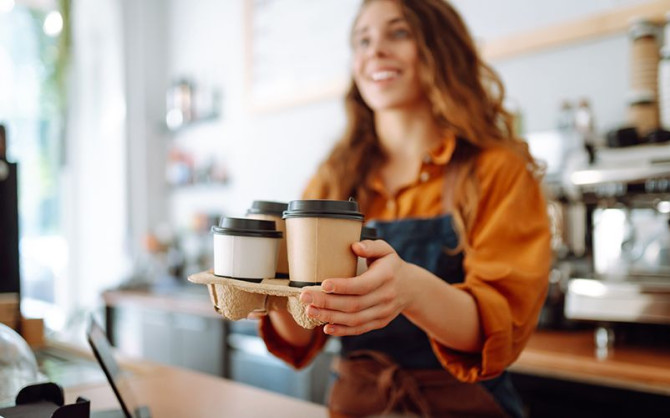 young-female-barista-holding-disposable-glasses-with-hot-drink.jpg